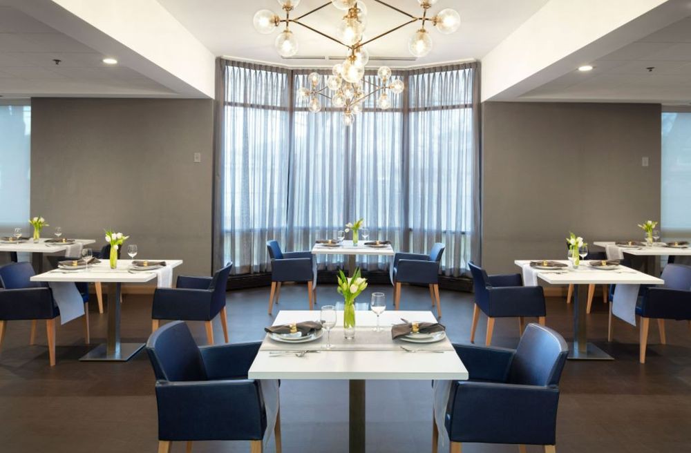 A modern restaurant interior with elegant dining tables and a striking chandelier.