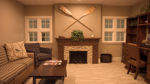 A cozy living room featuring a decorative fireplace, comfortable seating, and wooden paddles mounted on the wall.