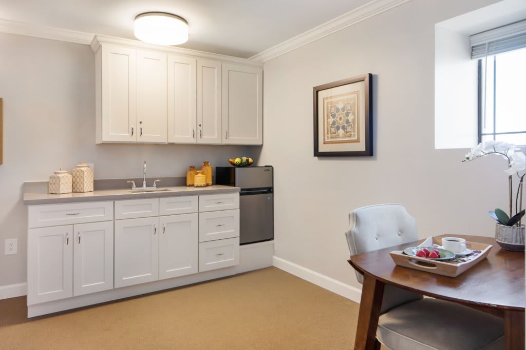 A cozy kitchenette with white cabinets and a small dining area.