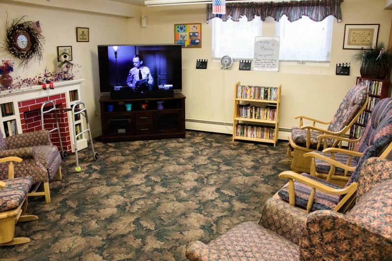 A cozy living room with a television and bookshelves filled with books.
