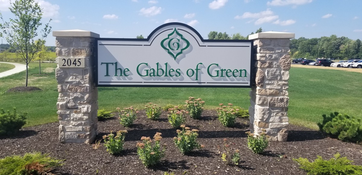 A sign reads 'The Gables of Green' surrounded by landscaped plants.