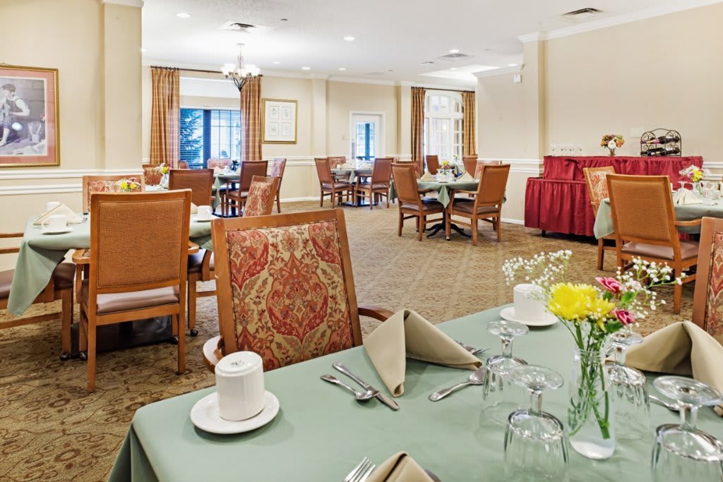 A well-decorated dining area with neatly set tables and chairs, featuring floral arrangements.