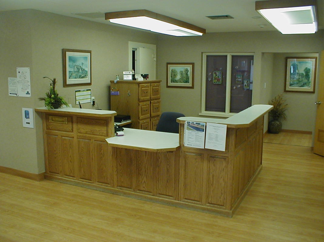 A reception office with a wooden desk and artwork on the walls.