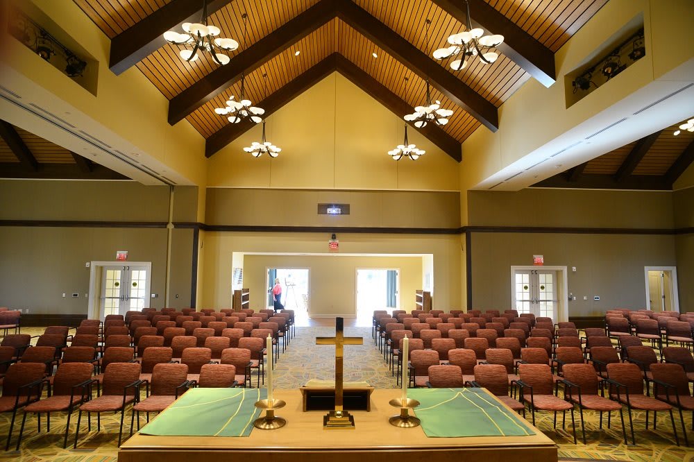 Interior view of a church with pews and an altar, featuring a prominent cross.