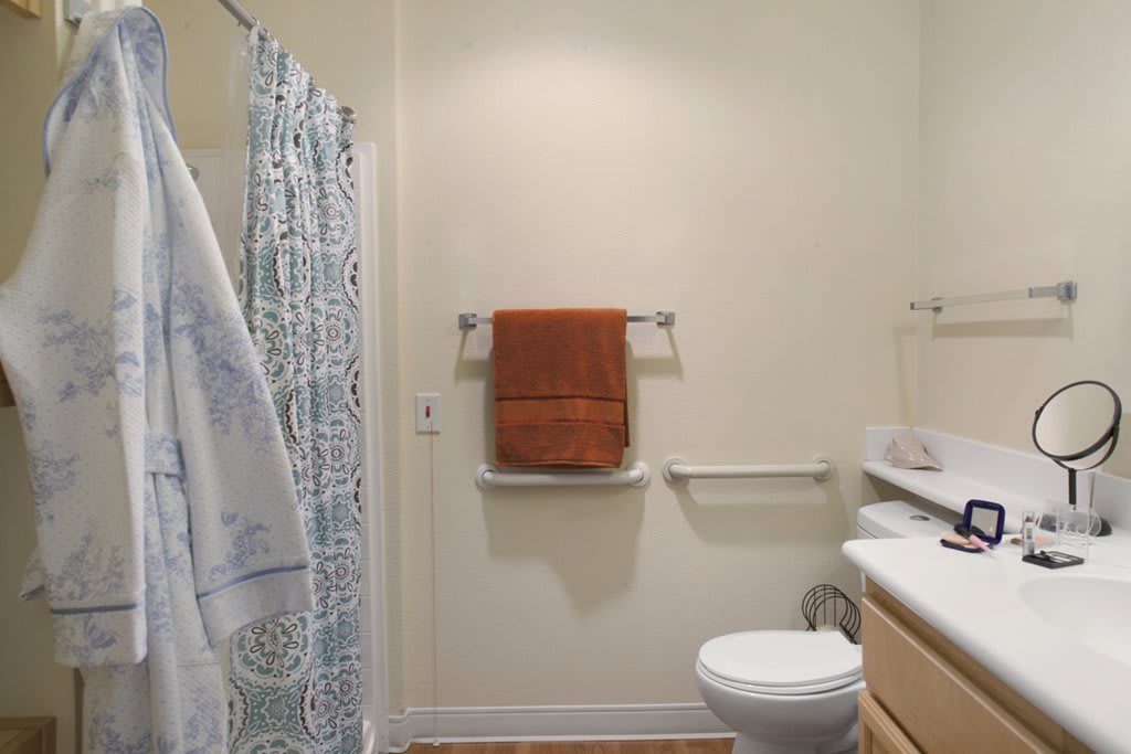 A clean bathroom with a shower curtain, toilet, sink, and orange towel.