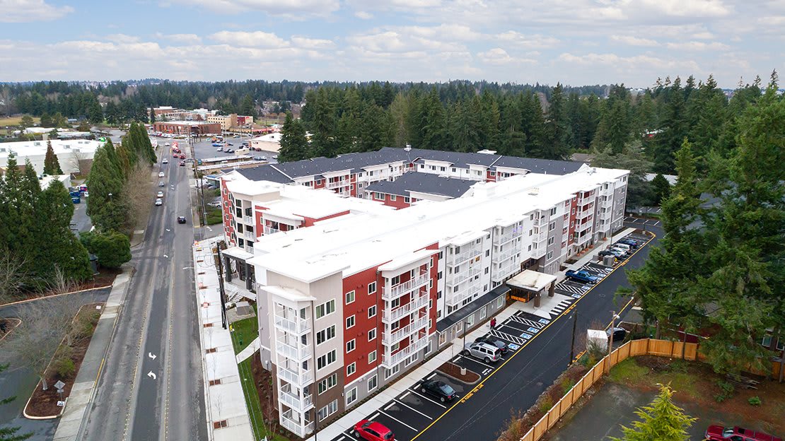 Aerial view of a modern apartment building with adjacent parking lot in an urban setting.
