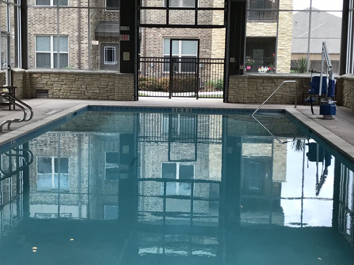 Indoor swimming pool with reflections of the surrounding apartment building.