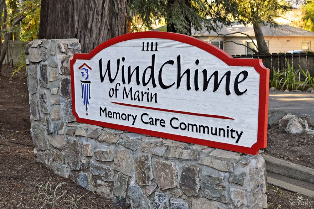 A sign for WindChime of Marin Memory Care Community mounted on a stone wall.