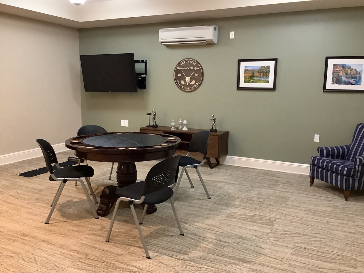A cozy room featuring a poker table with chairs, a television, and decorative wall art.