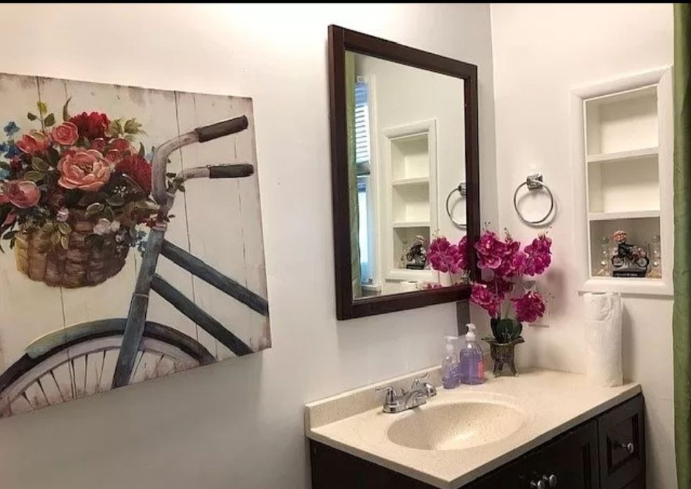 A well-decorated bathroom with a mirror, sink, and floral arrangement.