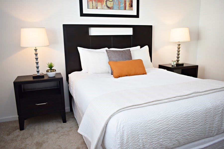 A modern bedroom with a neatly made bed, flanked by nightstands and lamps.