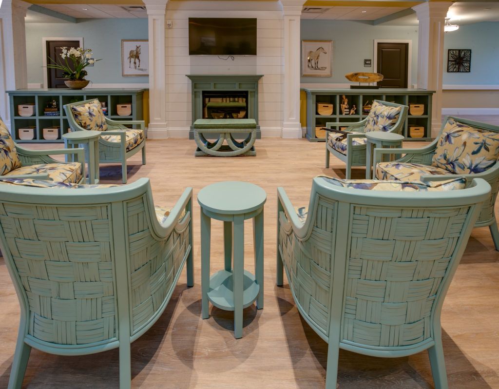 A cozy living room with pastel-colored furniture arranged around a central fireplace and television.