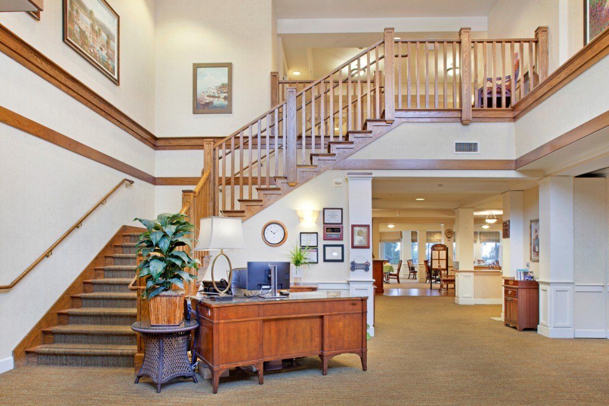 A spacious lobby area featuring a wooden desk, staircase, and plant decor.
