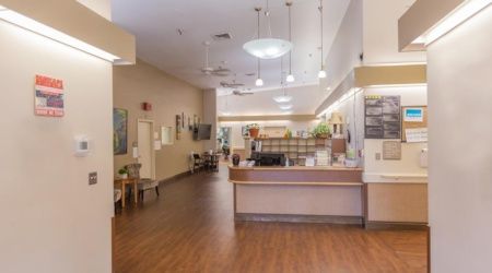 A well-lit nursing home lobby featuring a reception desk and comfortable seating.