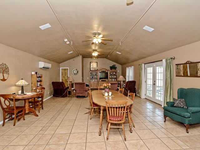 A spacious open-plan living and dining area with tiled flooring, featuring wooden furniture and a ceiling fan.