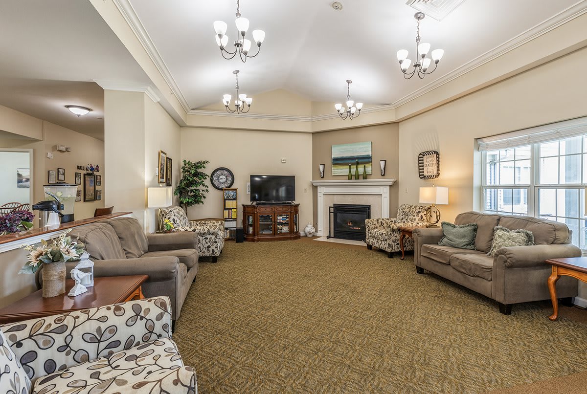 A spacious and elegantly decorated living room featuring multiple couches, a fireplace, and chandeliers.