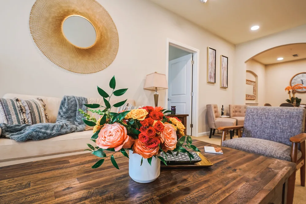 A stylish living room with a vibrant floral arrangement on a wooden table, featuring modern decor and cozy seating.