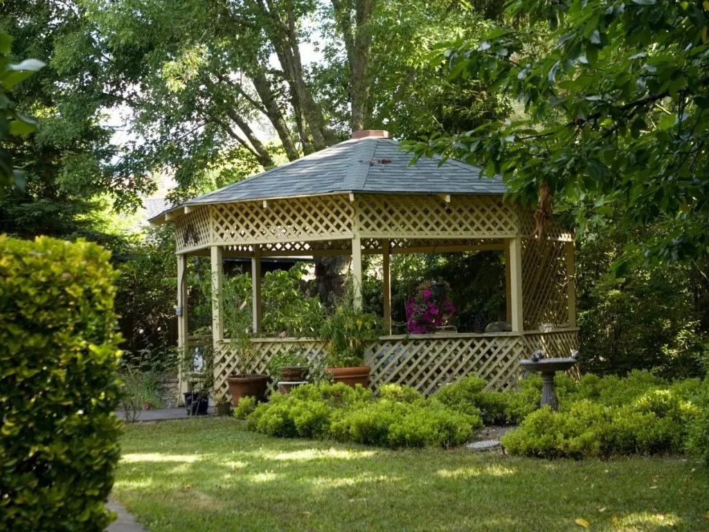A peaceful garden scene featuring a charming gazebo surrounded by lush greenery.