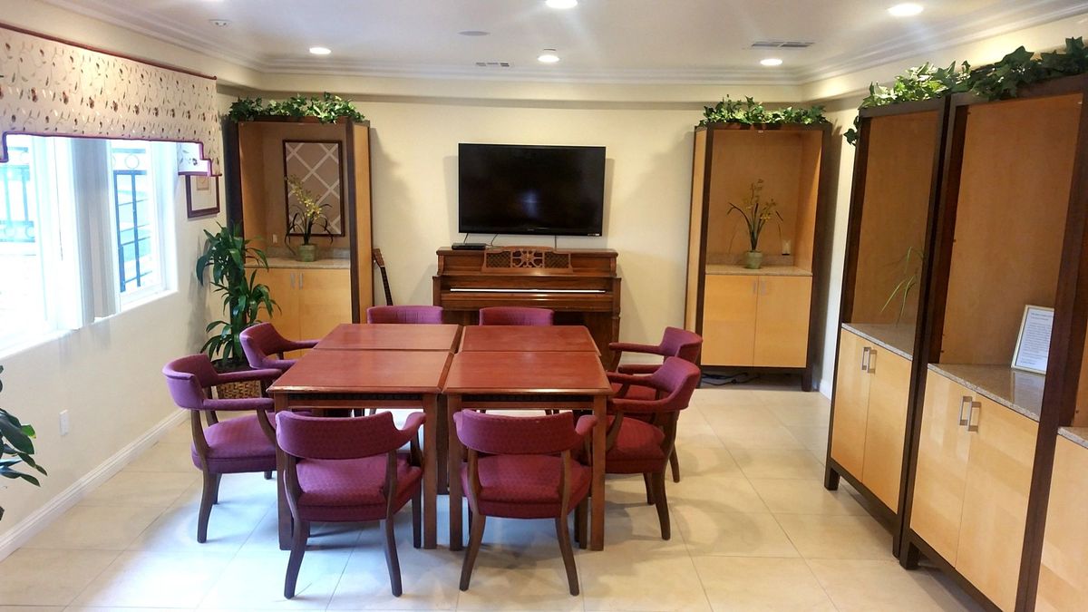 A cozy meeting room with a table, chairs, piano, and television.
