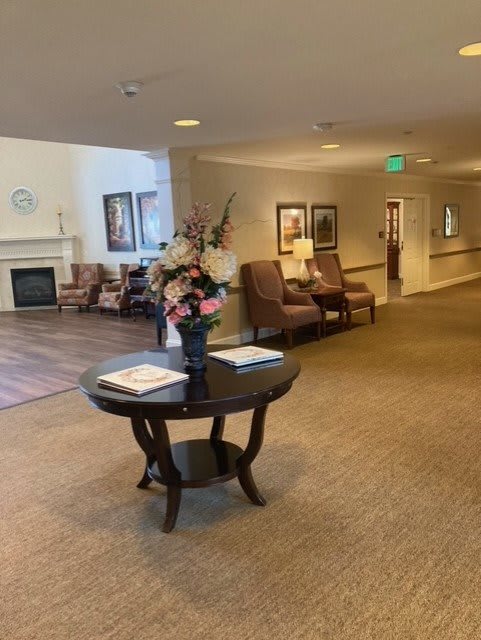 A well-decorated lobby featuring a round table with flowers, seating area, and carpeted flooring.