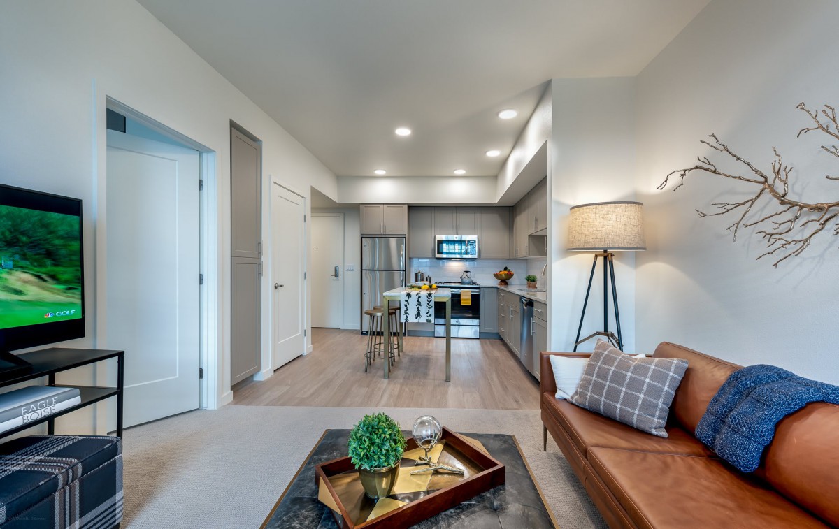 A modern open-concept living room with cozy seating and a view into the kitchen area.