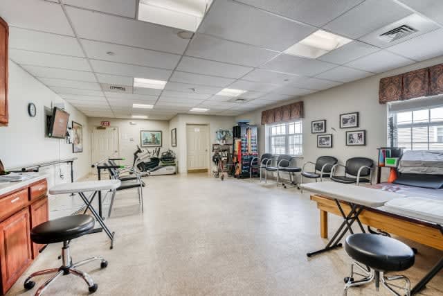 A spacious rehabilitation center featuring exercise equipment, treatment tables, and seating areas.