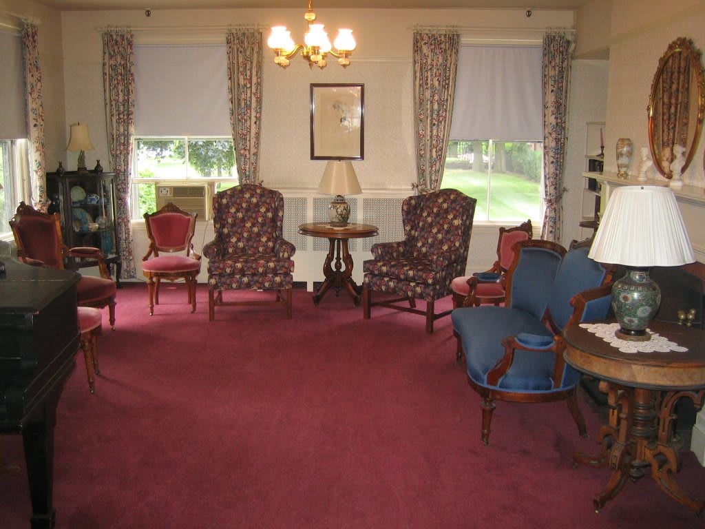 A vintage living room featuring classic armchairs, a rich carpet, and elegant curtains.
