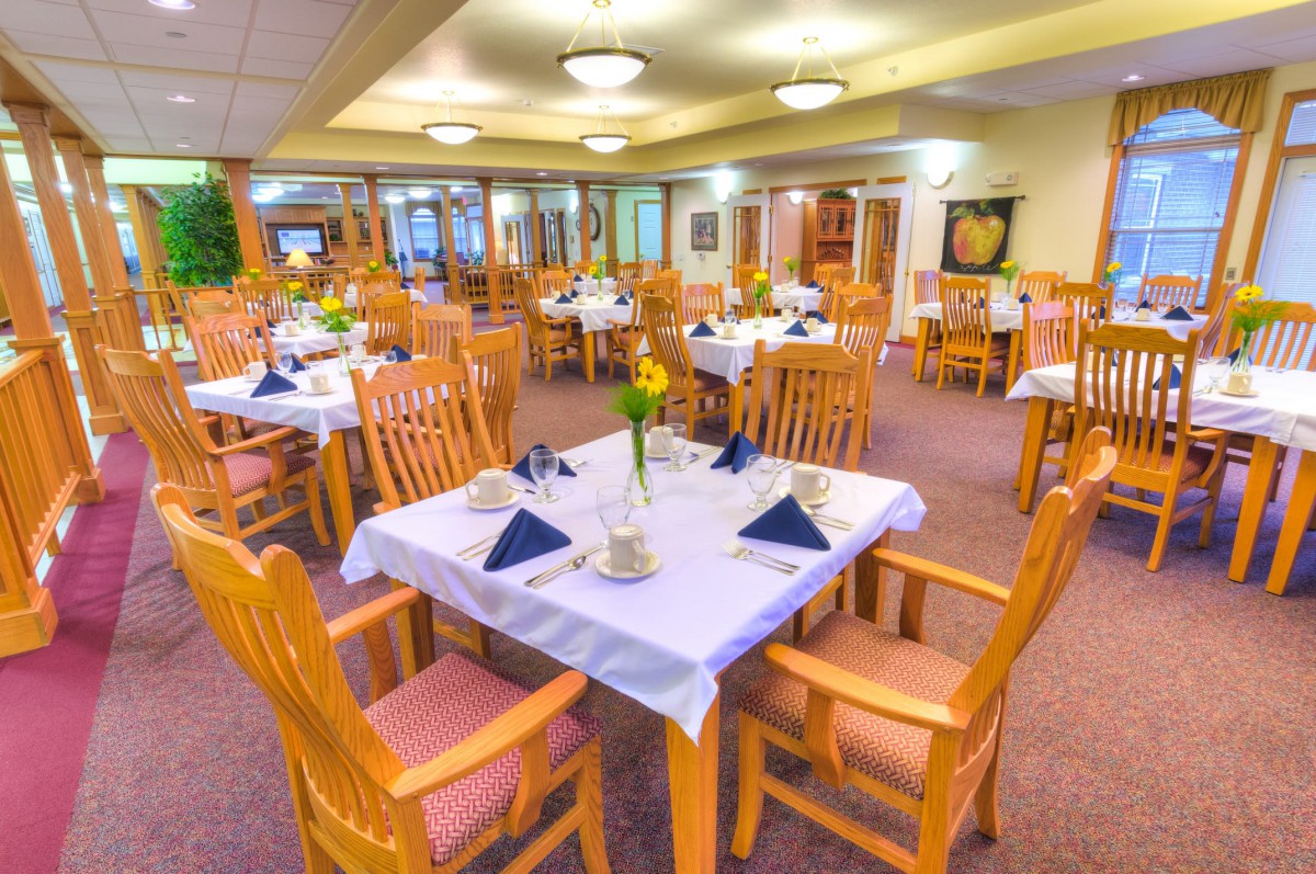 A well-arranged dining room with wooden furniture and elegantly set tables.