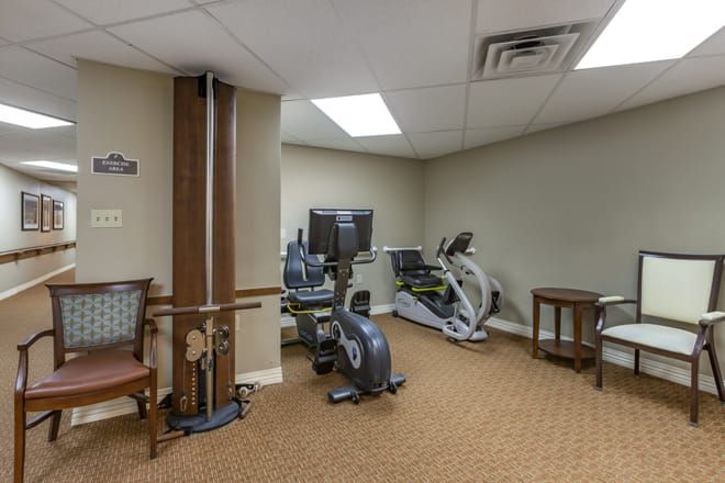 A small gym room with various exercise equipment, including an exercise bike and weight machine.