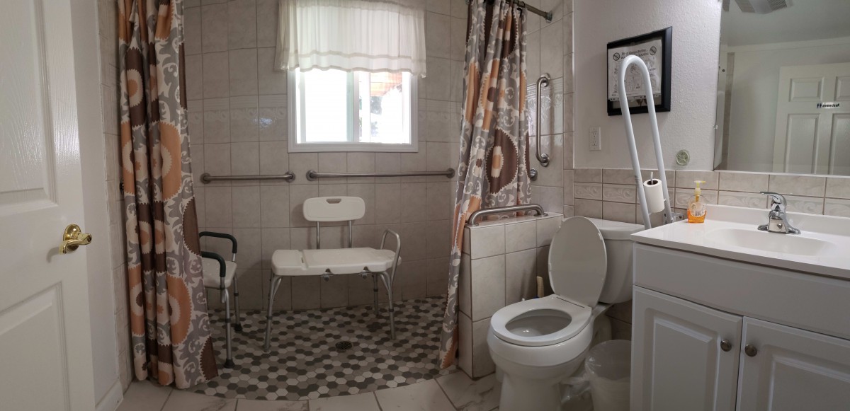 An accessible bathroom with a shower chair and grab bars.