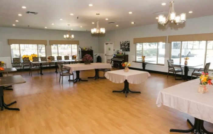 A spacious dining area with tables and chairs, illuminated by chandeliers.