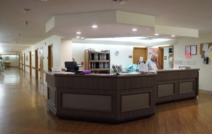 Hospital reception area with a nurse working at the desk.