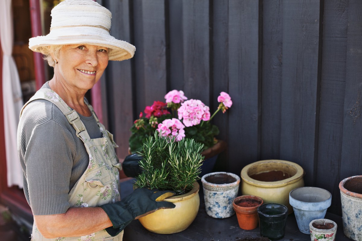 A woman happily gardening with potted flowers.