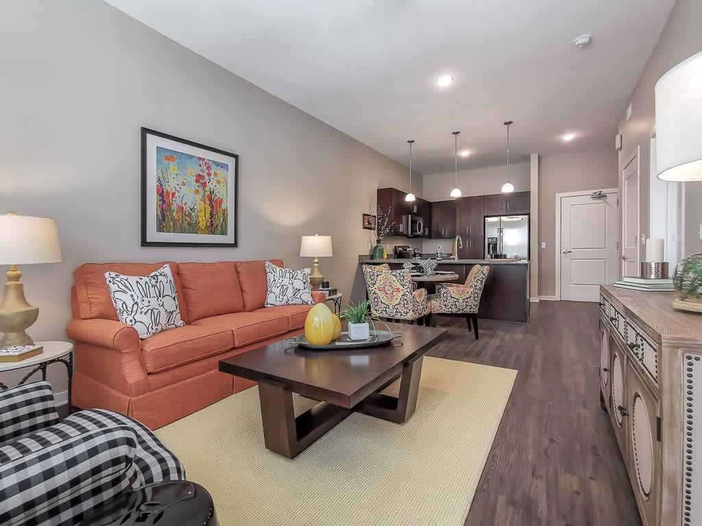 A modern living room with an open kitchen, featuring an orange sofa and stylish decor.