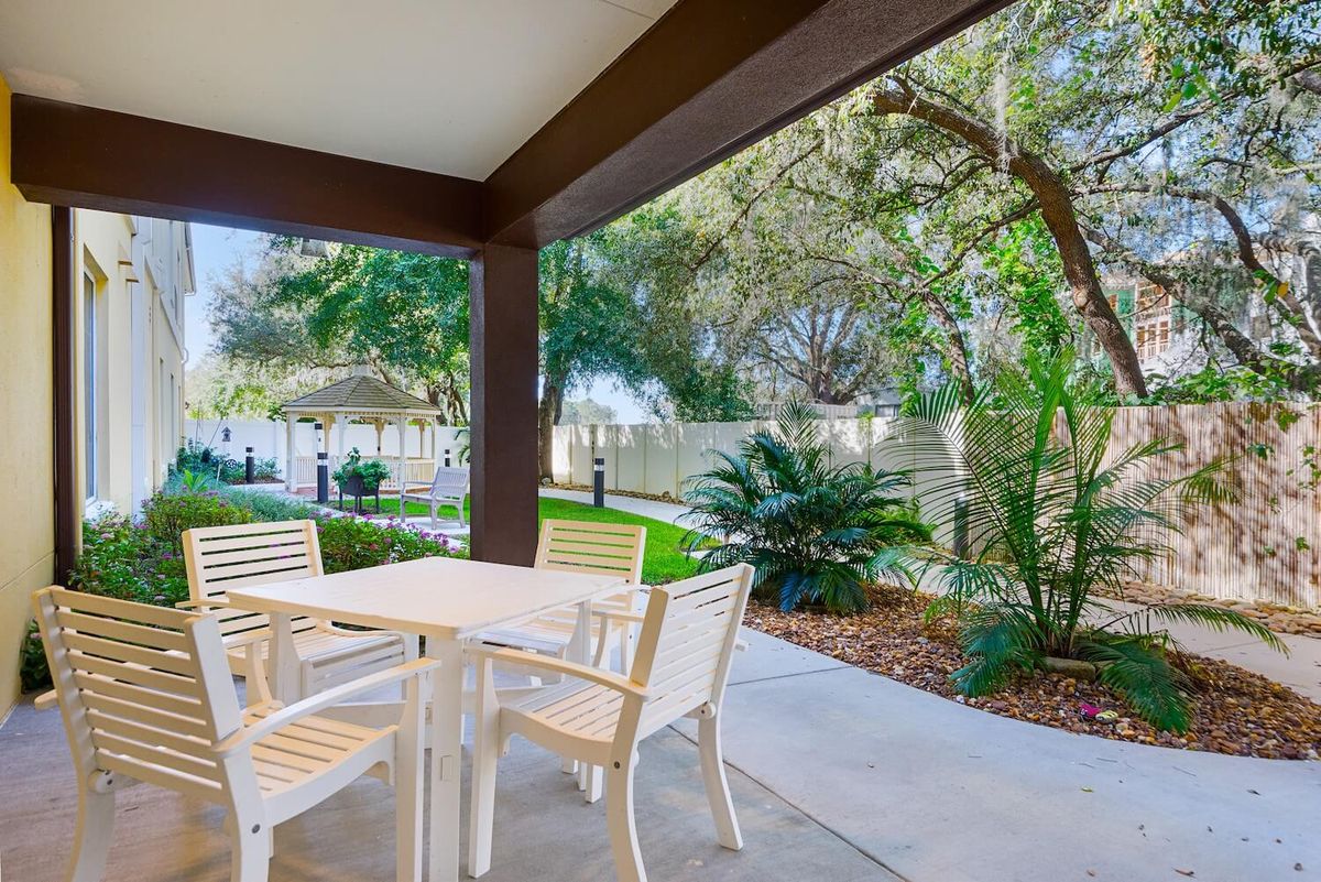A serene patio area with a table and chairs overlooking a landscaped garden.