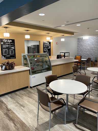 A modern cafe interior featuring a coffee bar, seating area, and an ice cream display.