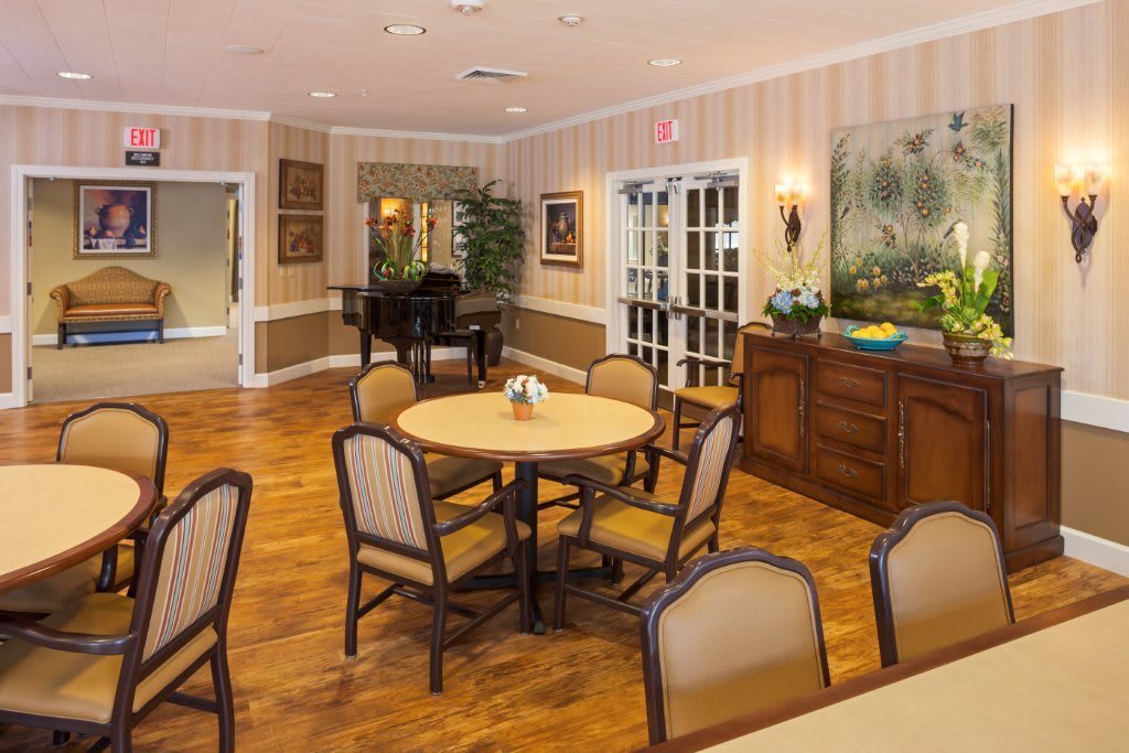 A cozy dining area with round tables and cushioned chairs, set on a polished wooden floor, adorned with wall art and decor.