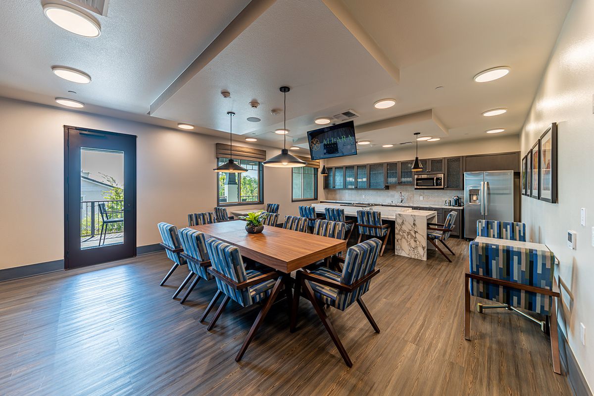 A modern dining and kitchen area with a large wooden table and stylish chairs.