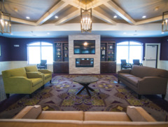 A spacious living room with a high ceiling, elegant chandelier, and comfortable seating arranged around a central table.