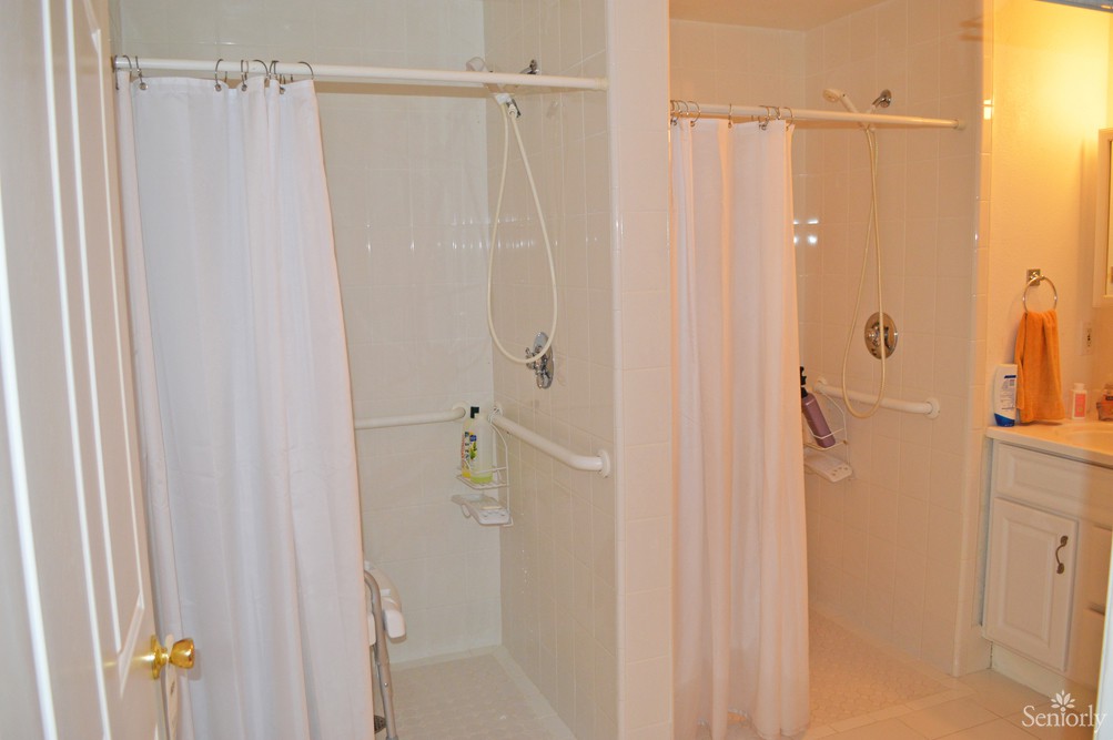 A bathroom with two shower stalls featuring white curtains.
