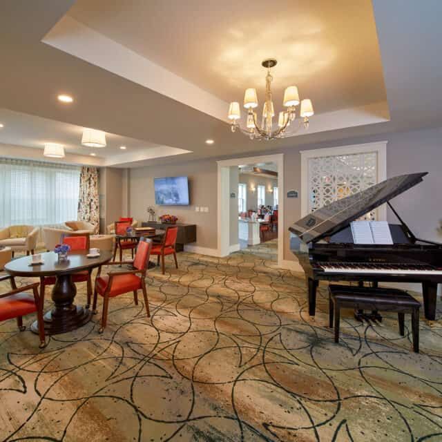 A well-appointed living room featuring a grand piano, elegant chandelier, and comfortable seating arrangements.