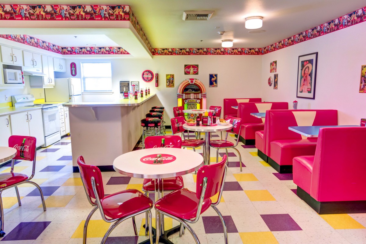 A retro 1950s-style diner with vibrant red booths, a classic jukebox, and a colorful checkered floor.