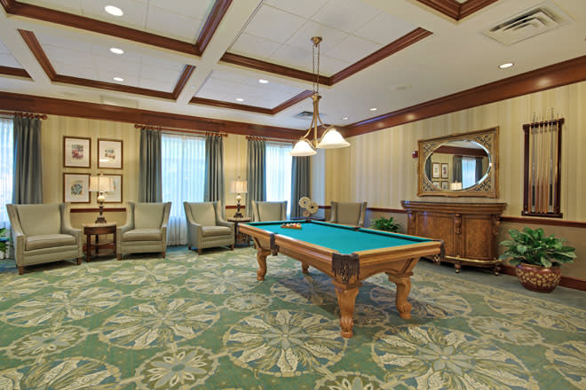 A luxurious billiard room with a pool table, elegant chairs, and sophisticated decor.