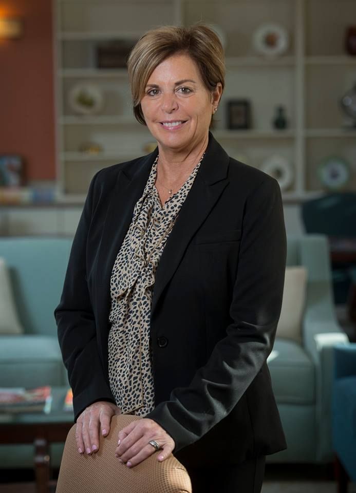 A professional woman standing indoors in an office setting.