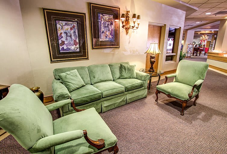 A cozy living room featuring green upholstered furniture and wall art.