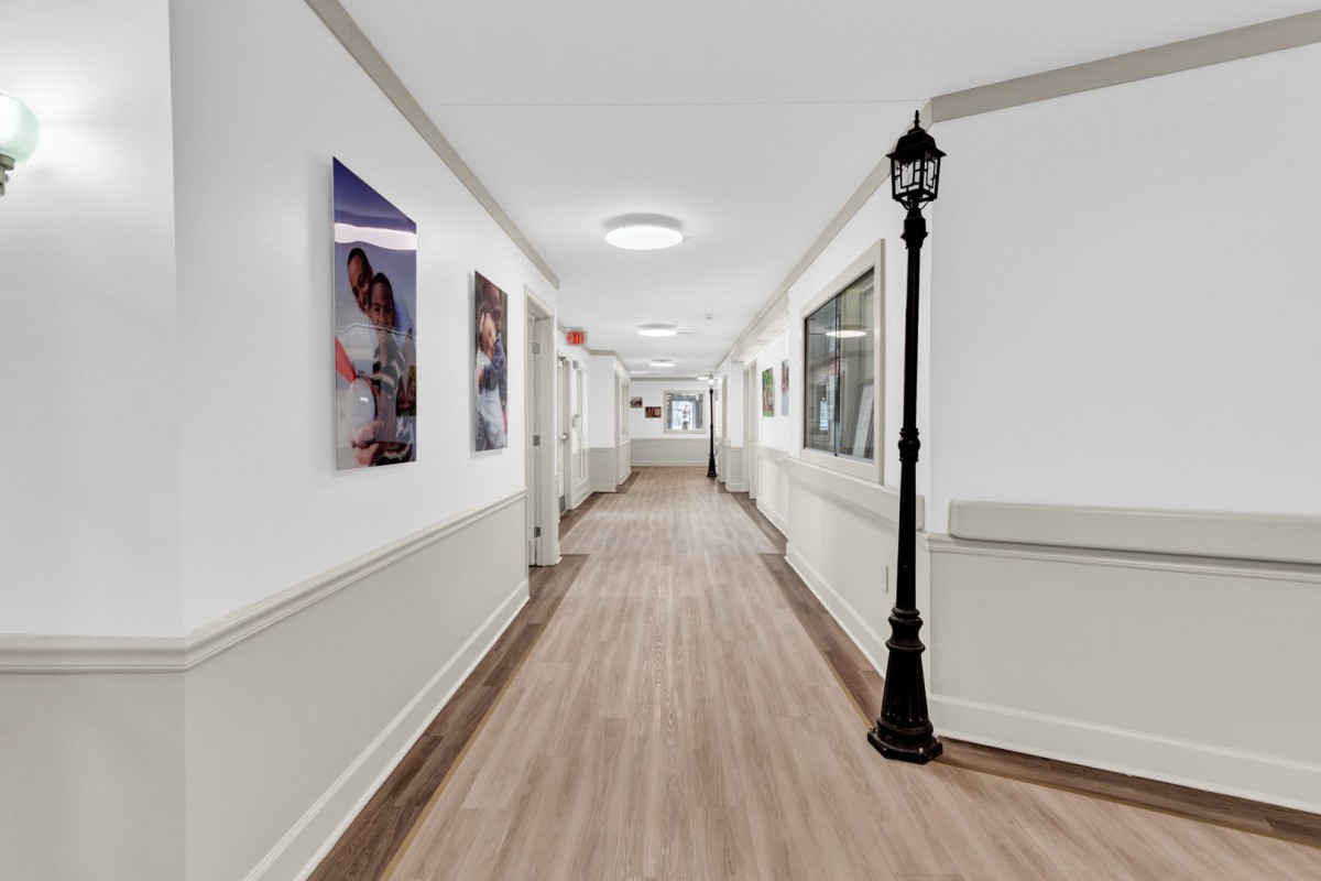 A well-lit hallway with pictures on the walls and a decorative lamppost.