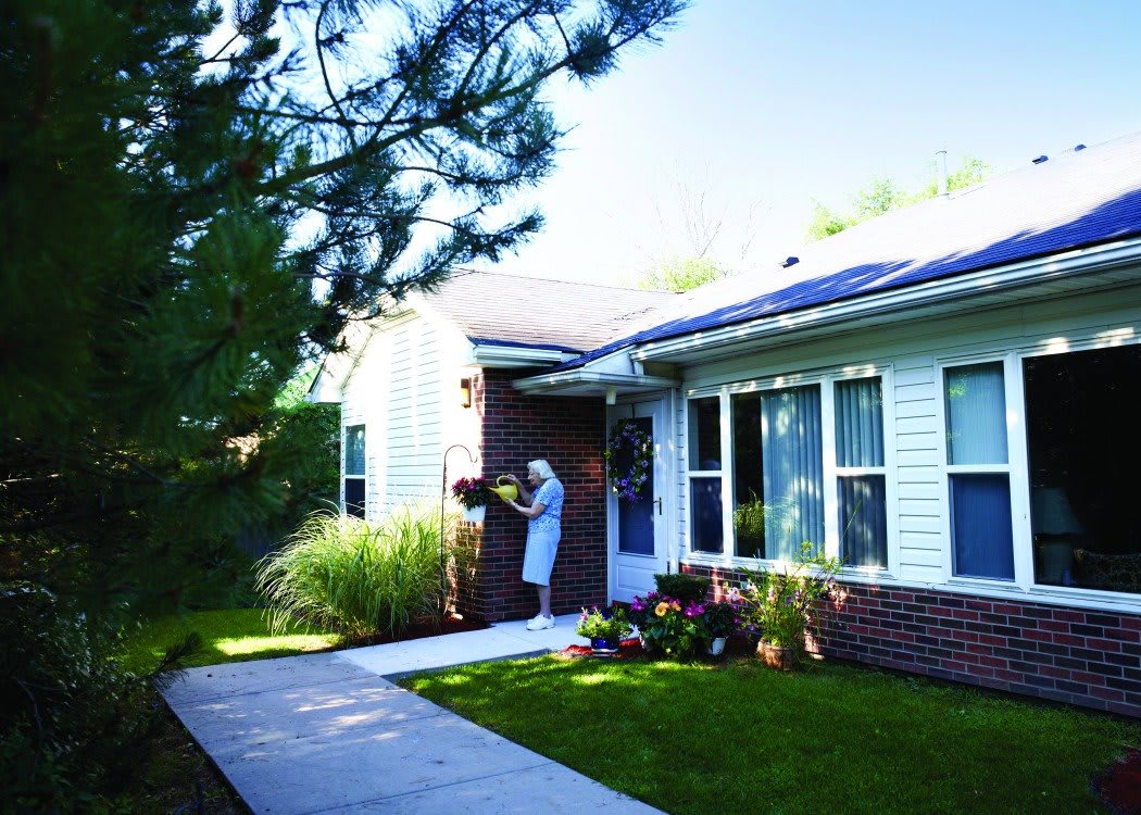 A person tending to the garden outside a house with solar panels on the roof.