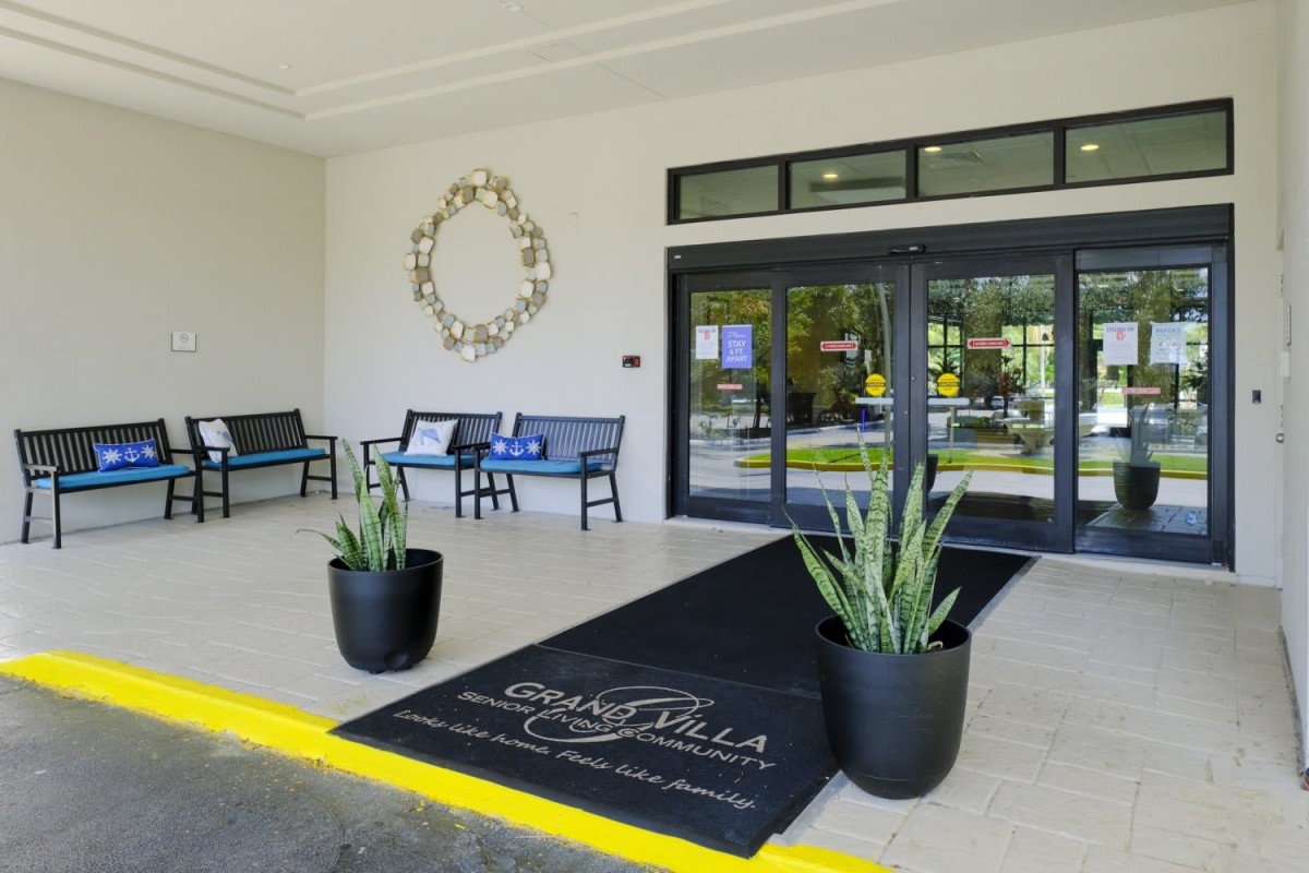 A modern building entrance with decorative plants and seating.