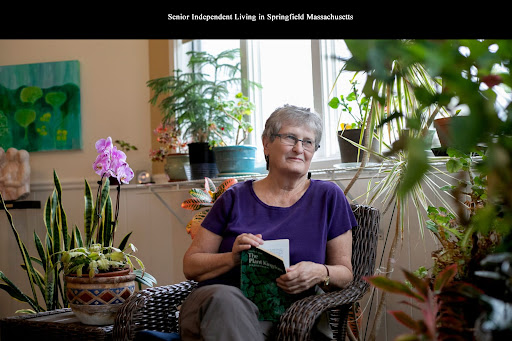 A resident of an independent living community in Springfield, Massachusetts, enjoying a moment of relaxation surrounded by plants while writing.