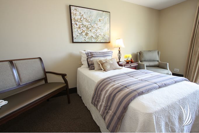 A cozy bedroom with a neatly made bed, decorative pillows, and a wall painting above it.